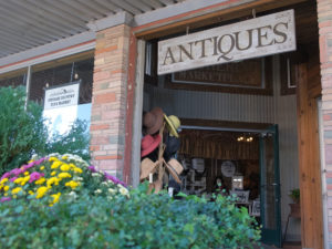 Brick storefront with hanging wood sign reading Antiques